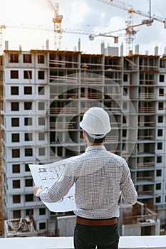 Construction site supervision builder or architect in hard hat overseeing project with blueprints photo