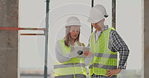 Construction site team or architect and builder or worker with helmets discuss on a scaffold construction plan or