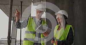 Construction site team or architect and builder or worker with helmets discuss on a scaffold construction plan or