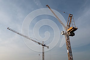 Construction site with two yellow cranes against blue sky