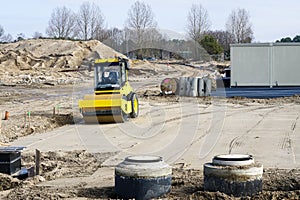 Construction site with underground pipeline wells, road roller and high voltage distribution box