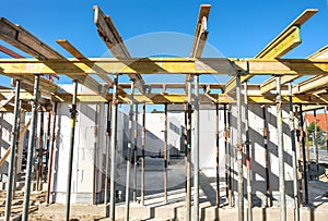 House building: Shell of a new house with ceiling supports at a site and blue sky