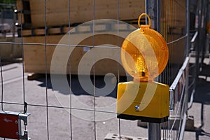 Construction site warning lamp on a construction fence in front of a container