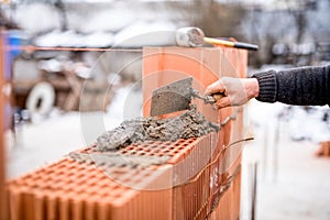 Construction site with worker building brick walls with mortar and bricks
