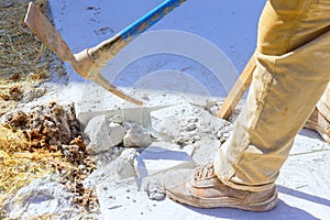 Construction site worker smashes concrete driveway with pickaxe