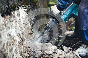 construction site with worker using pneumatic jackhammer for demolishing a structural wall