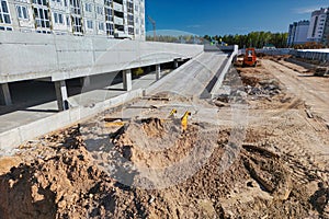 A construction site with workers and machinery in front of a massive building, showing ongoing construction activity