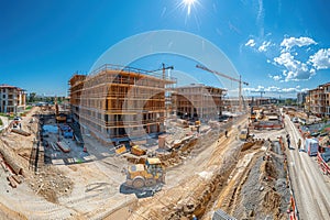 Construction site with a yellow tractor and two cranes under the bright sun