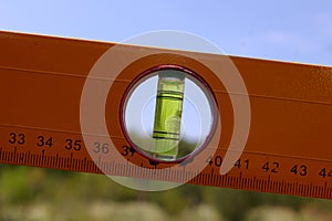 Construction spirit level tool on natural summer background. Bubble level instrument for calibration, levelling, and