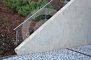Construction of a steep staircase near a concrete wall. railing above the sloping sloping retaining wall above which ornamental sh