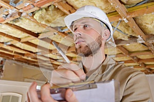 construction supervisor writes on clipboard