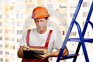 Construction supervisor writes on clipboard.