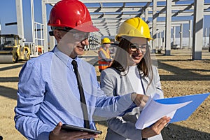 Construction Supervisor And Young Female Architect Checking Project Documents At Construction Site