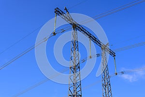 Construction of a support and wires of a high-voltage power line close-up against a blue sky