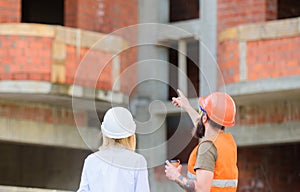 Construction team communication concept. Discussing plan. Woman engineer and builder communicate at construction site