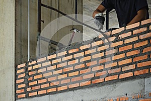 Construction technician work in brickwork using trowel putty knife bricklayer  installing brick masonry on an interior wall within