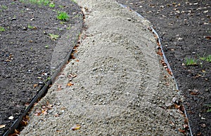 Construction of a threshing gravel sidewalk, installation of a steel strip as a curb path. between them there is a gravel mixture