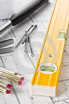 Construction tools with hammer, nails, folding rule and level on architectural blueprint plan