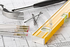 Construction tools with hammer, nails, folding rule and level on architectural blueprint plan