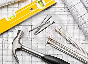 Construction tools with hammer, nails, folding rule and level on architectural blueprint plan flat lay