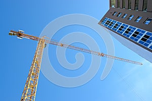 Construction tower crane and new building over blue sky background.