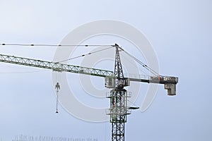 Construction tower crane over a multi-story apartment building under construction. Housing market, real estate, crisis