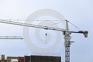 Construction tower cranes over multi-story apartment building under construction. Housing market, real estate, crisis