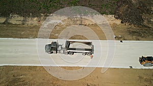 Construction truck tipping dumping gravel on road construction site, aerial above view footage