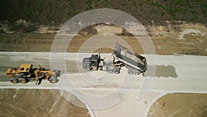 Construction truck tipping dumping gravel on road construction site, Drone top view footage