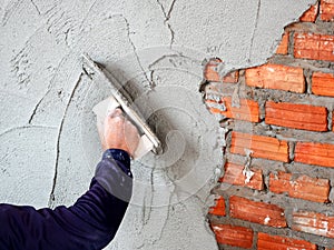 Construction under building with mason plastering concrete to brick wall
