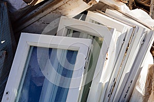 Construction waste for disposal. Heap of old wooden window frames with glass outdoors. Renovation and reconstruction