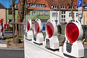 Construction of white barrier at a road with red reflecting lamps as safety installation