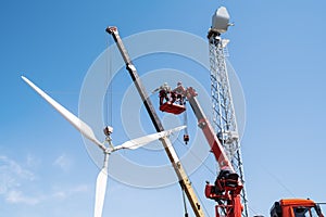 Construction of a wind power plant. Installers use a truck crane and aerial platform to raise the wind turbine rotor