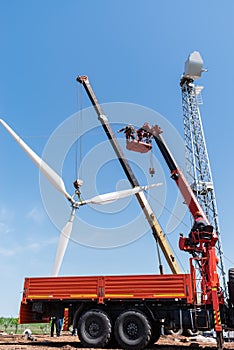 Construction of a wind power plant. Installers use a truck crane and aerial platform to raise the wind turbine rotor