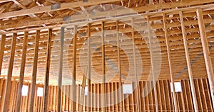 During the construction of a wooden building, an interior view of wood beams and truss rafters supports wood beam