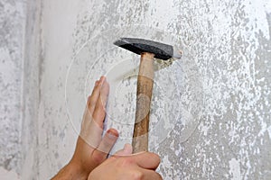 Construction work, a hammer hammers a dowel into the wall, close-up