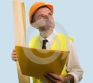 Construction work lifestyle portrait of young happy and attractive engineer or building contractor holding blueprints wearing
