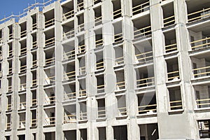 Construction work site of a multi-storey building showing frames of naked concrete walls with empty spaces. Contruction workes pro