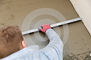 Construction worker aligns concrete screed floor