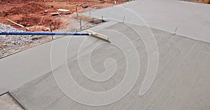 Construction worker applies a broom brushing pattern to freshly poured concrete in an attempt to texture it