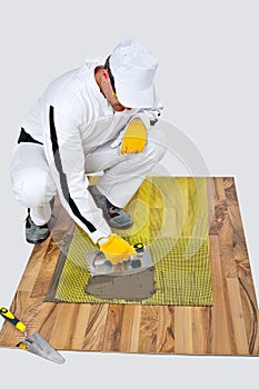 Construction worker applyes tile adhesive on wooden floor