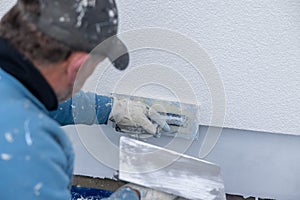 Worker plastering wall facade using hand trowel