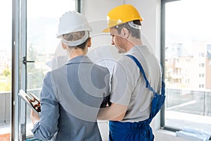 Construction worker and architect looking at plan on site