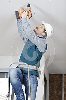 Construction worker assemble suspended ceiling with drywall