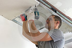 Construction worker assemble a suspended ceiling with drywall an