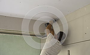 Construction worker assemble a suspended ceiling with drywall