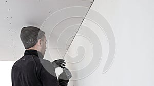 Construction worker assemble a suspended ceiling with drywall and fixing the drywall to the ceiling metal frame with