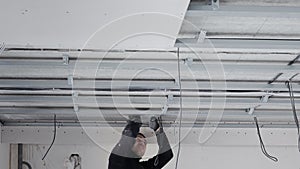 Construction worker assemble a suspended ceiling with drywall and fixing the drywall to the ceiling metal frame with