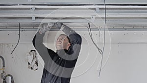 Construction worker assemble a suspended ceiling with drywall and fixing the drywall to the ceiling metal frame with