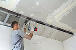 Construction worker assemble a suspended ceiling with drywall an